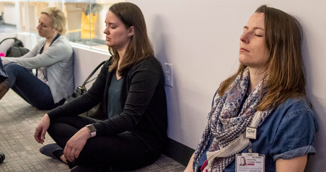 Three physicians sit with their eyes closed during a meditation session