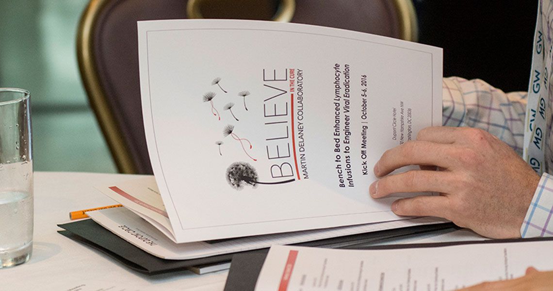 Person opening a packet titled 'Believe' at a table