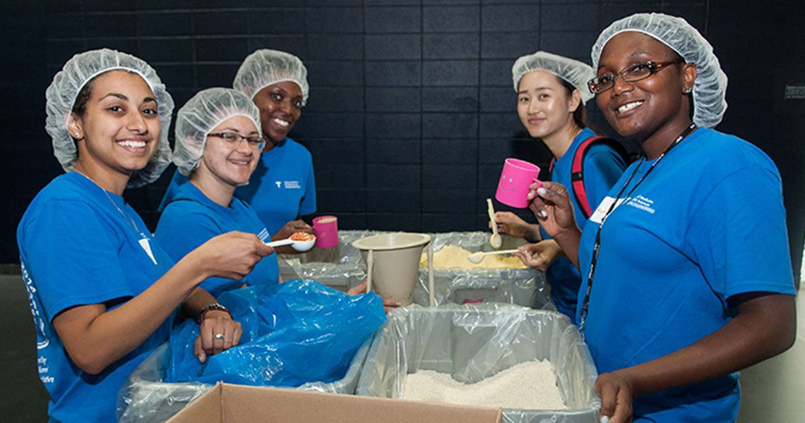 Student volunteers scooping rice and grains