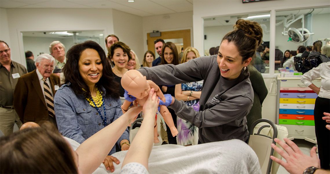 Student Kathleen Bren, with Patricia Smith, delivers a mannequin baby in the CLASS center