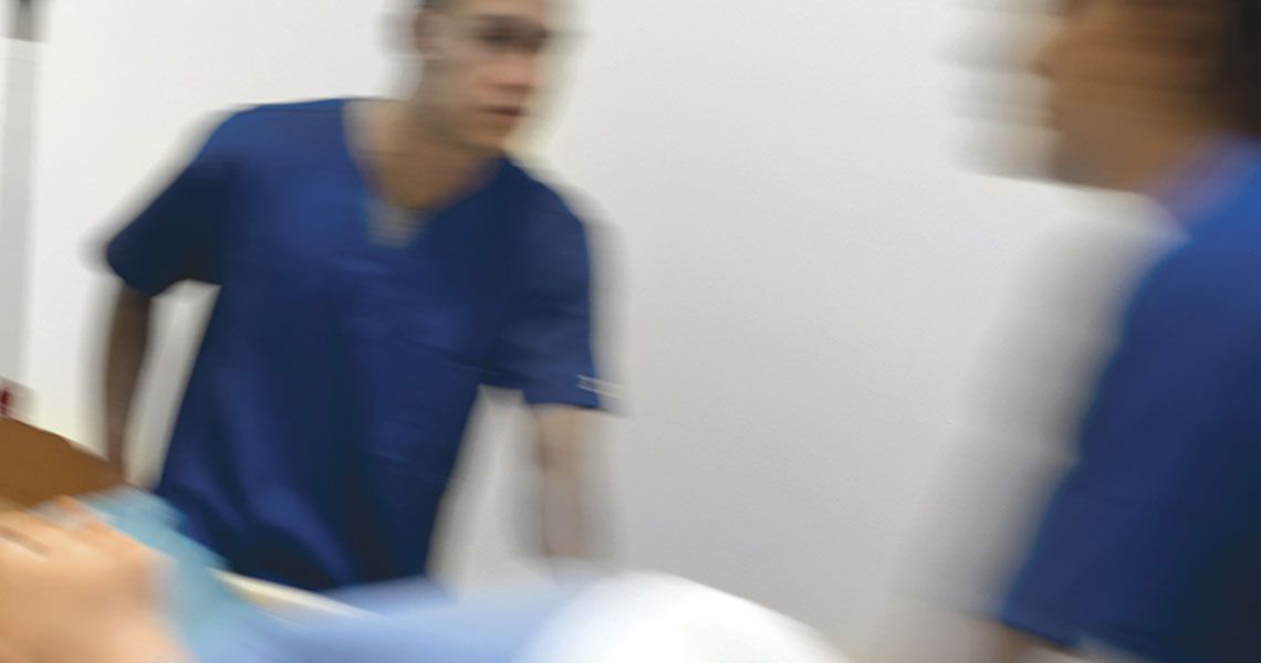 Medical providers in scrubs moving in blurred motion with a patient