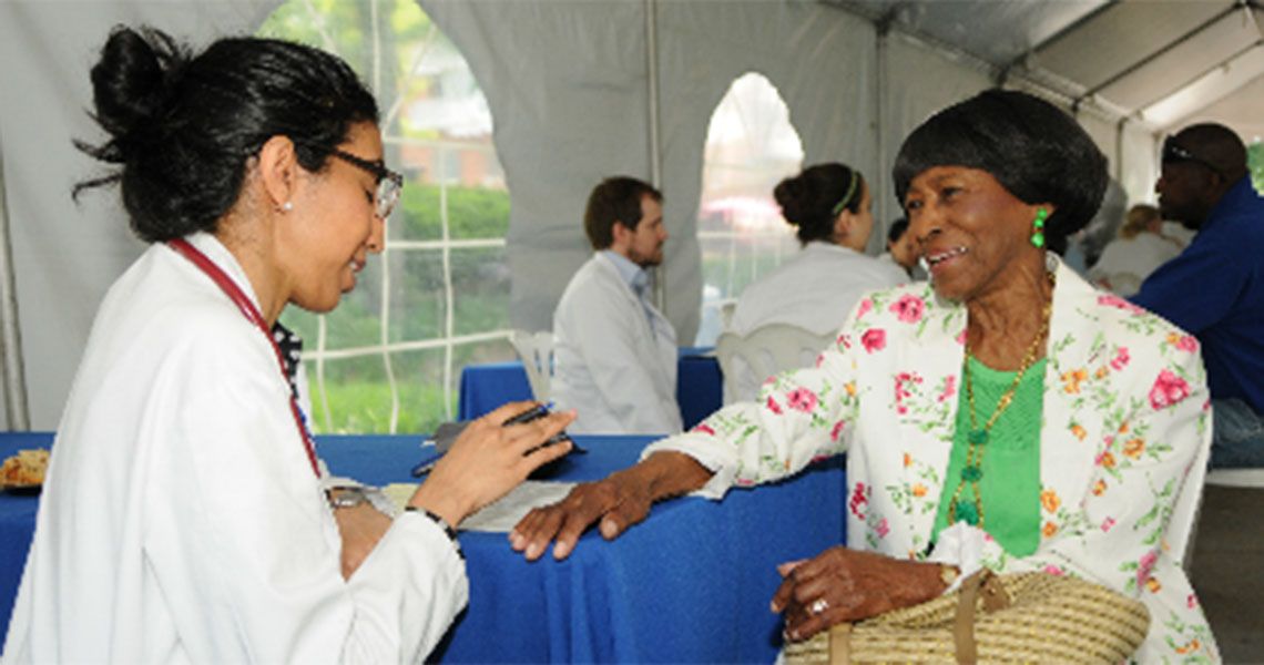 A GW medical provider screens a community member for stroke under a pop-up tent
