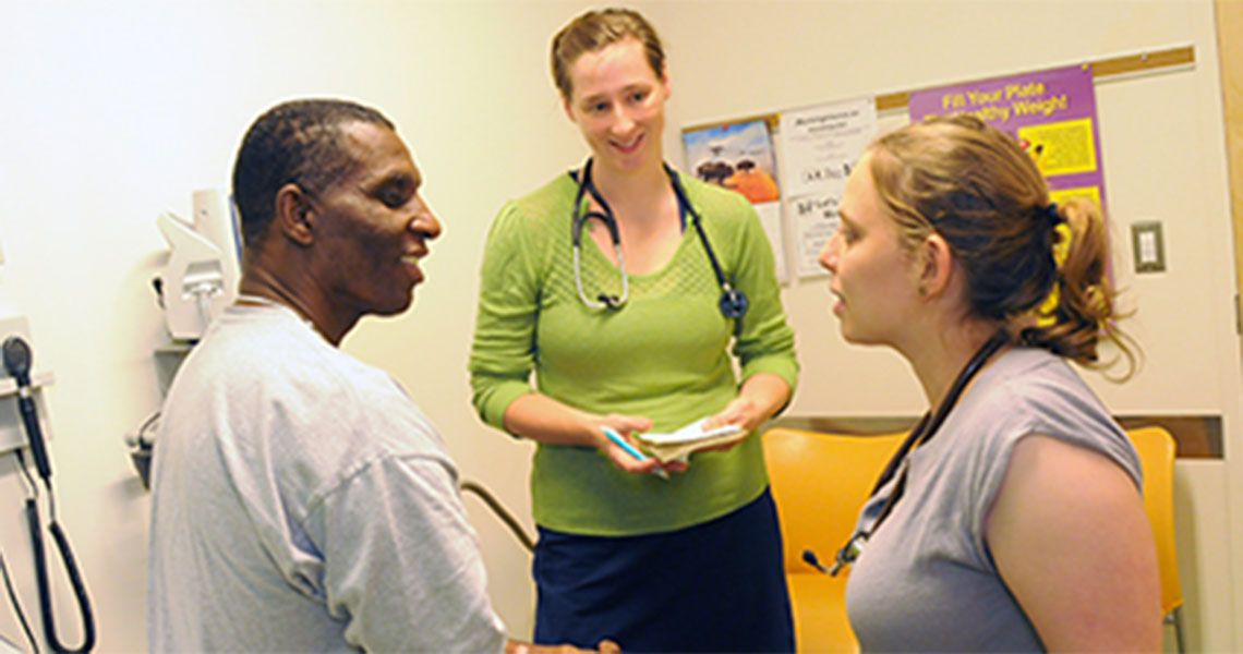 Two health care providers standing with a patient in an examination room