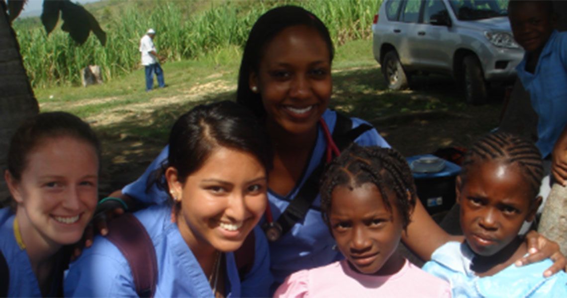Medical volunteers in blue scrubs posing with Haitian children