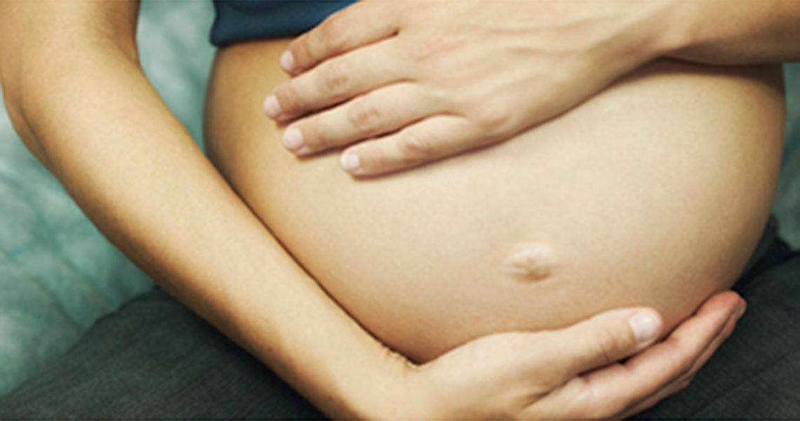 A pregnant woman clutching her exposed stomach