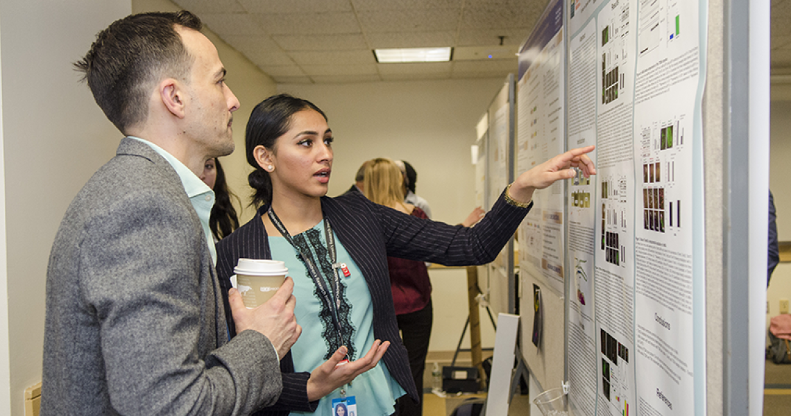 A female researcher points at a research poster