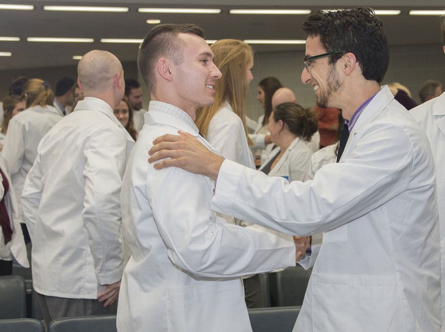 Two students shake hands at the Physical Therapy convocation
