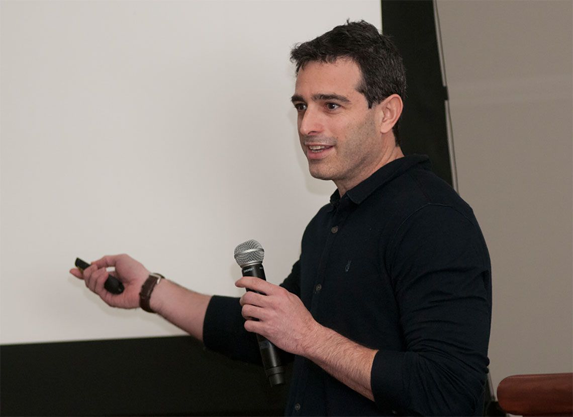 Dr. Yoav Gilad speaking into a microphone 