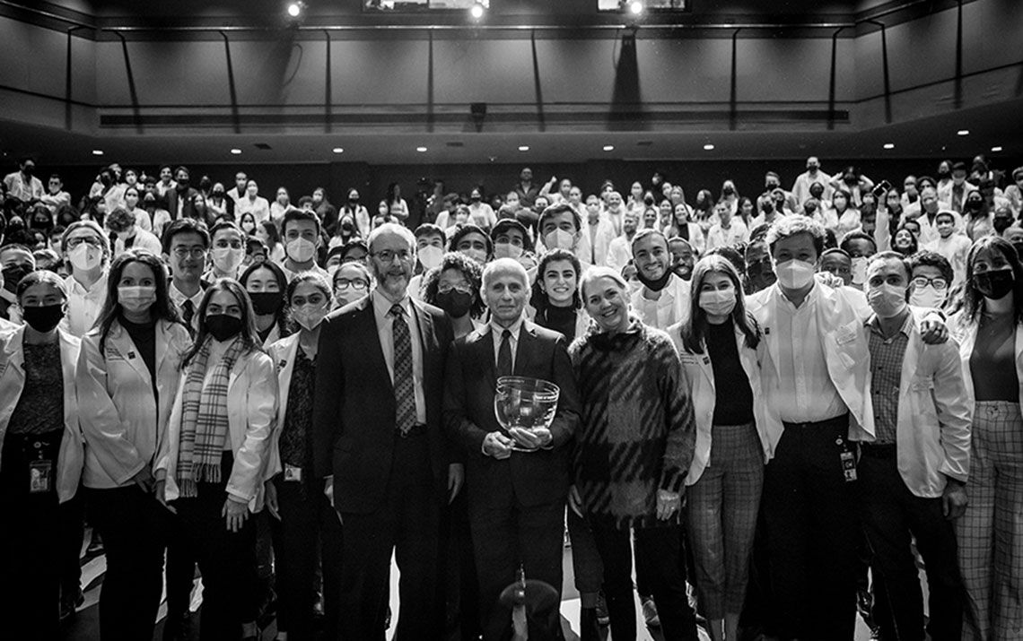 Anthony Fauci standing with Lawrence Deyton, Barbara Bass, and first-year SMHS MD students in an auditorium