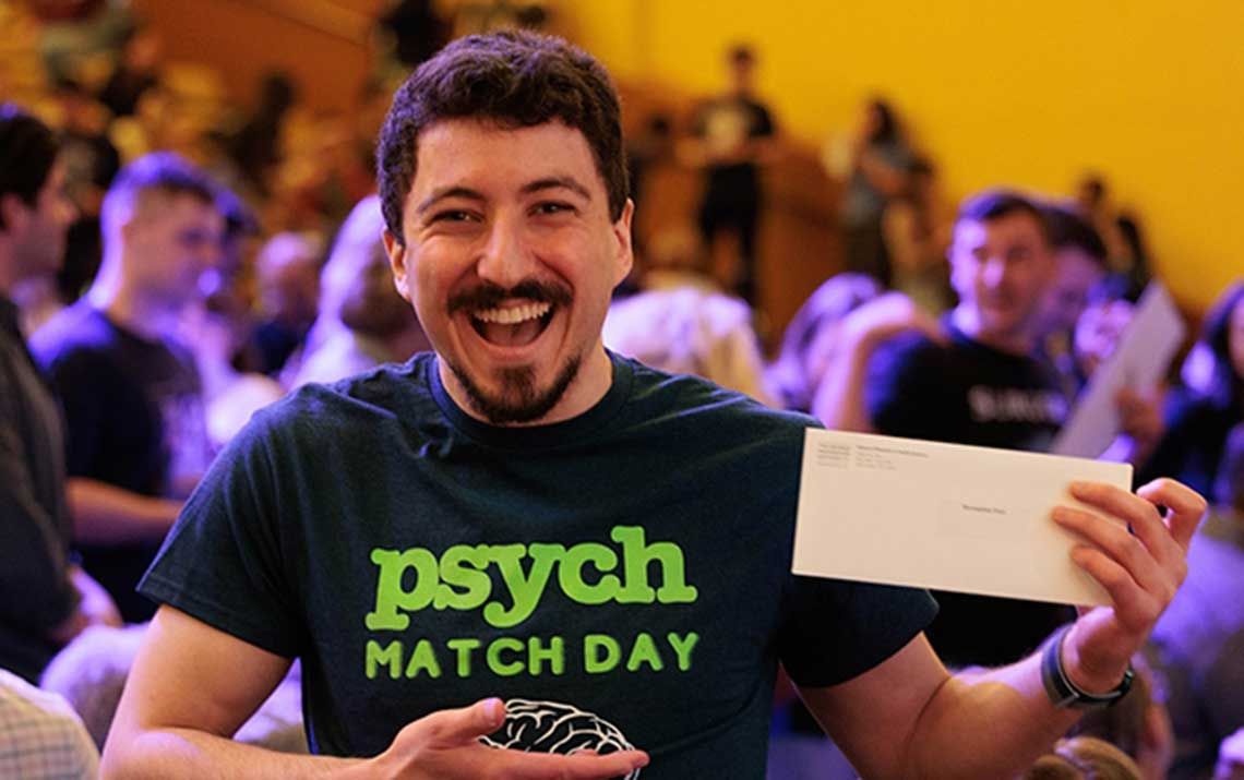 A student posing with their Match Day envelope