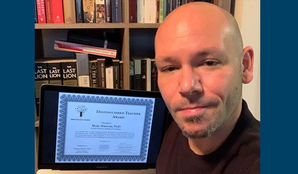 Dr. Marc Spencer posing with a certificate