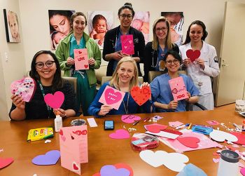 Several physicians hold up valentine's day cards and paper hearts