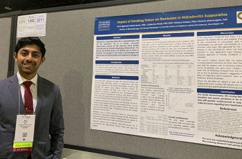 Amil Agarwal standing in front of his presentation poster
