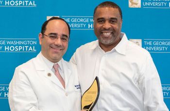 Dr. Babak Sarani standing with Dewayne Brown and holding a gold plaque
