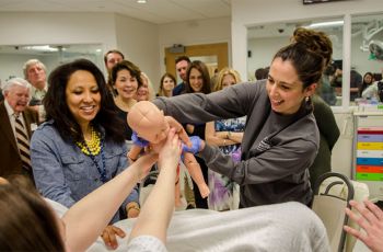 Student Kathleen Bren, with Patricia Smith, delivers a mannequin baby in the CLASS center