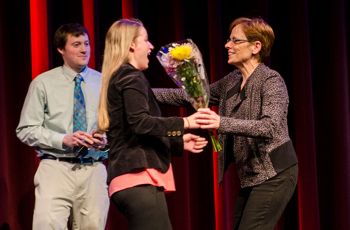 Student gives faculty member flowers at ceremony