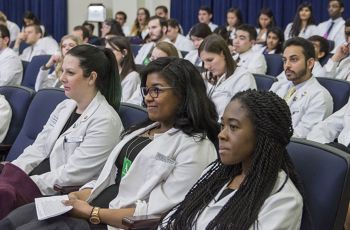 Students in white coats sitting in an auditorium