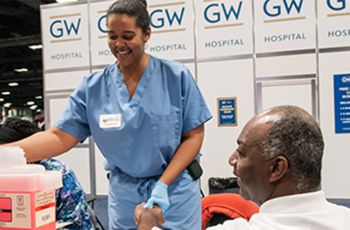 A GW Hospital medical volunteer worker with a community member at expo booth