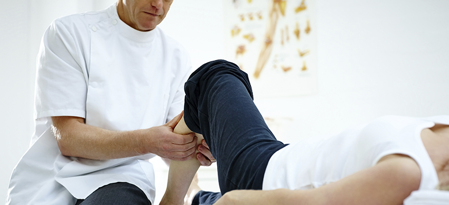 Physical therapist working on a patient's calf in a clinical setting.