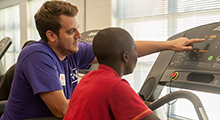 A PT student showing a child how to use a treadmill