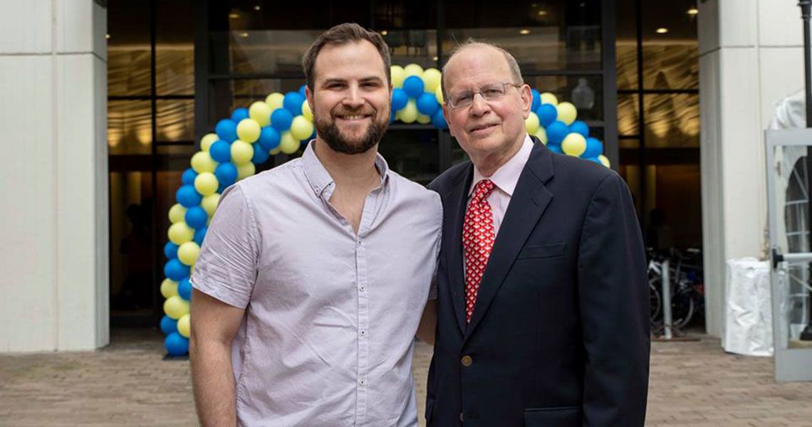 Dr. Art Sober standing with a student in front of a balloon archway