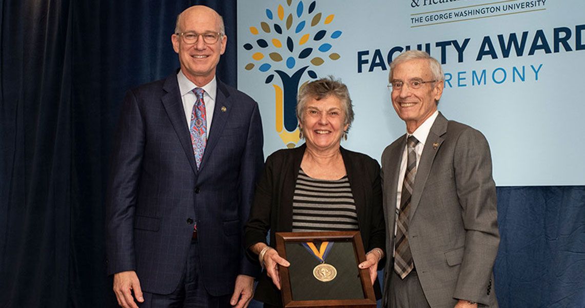A woman standing in between two men holding an award