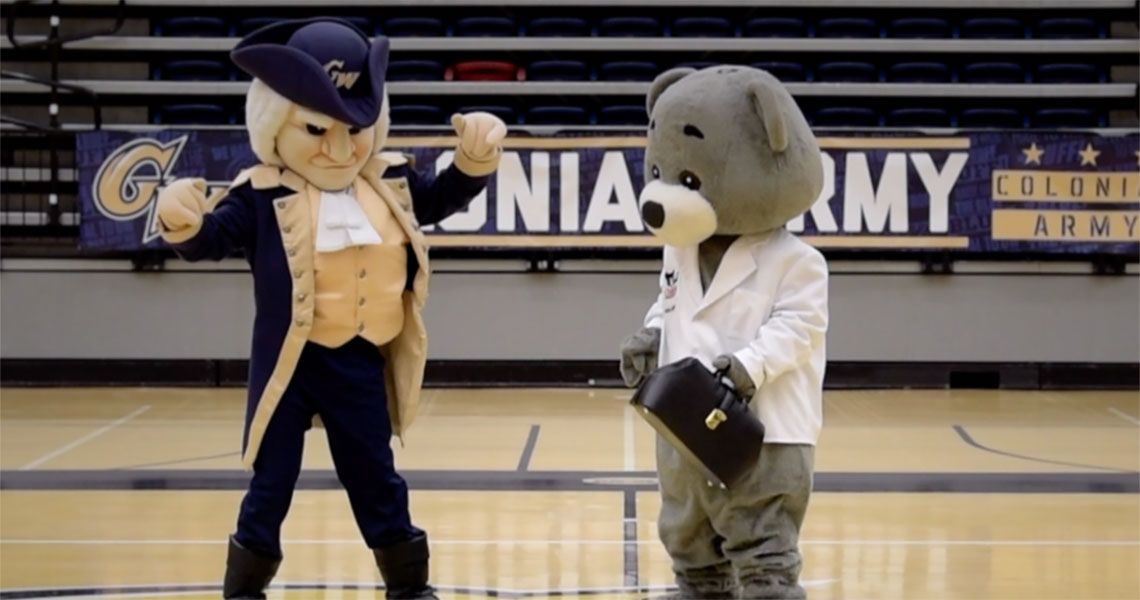 The George Washington and Dr. Bear mascots standing together on the GW basketball court