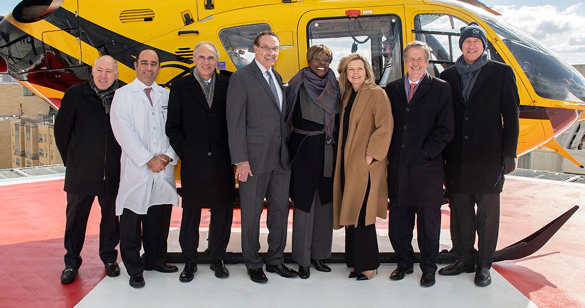 Several GW medical faculty stand in front of a yellow helicopter