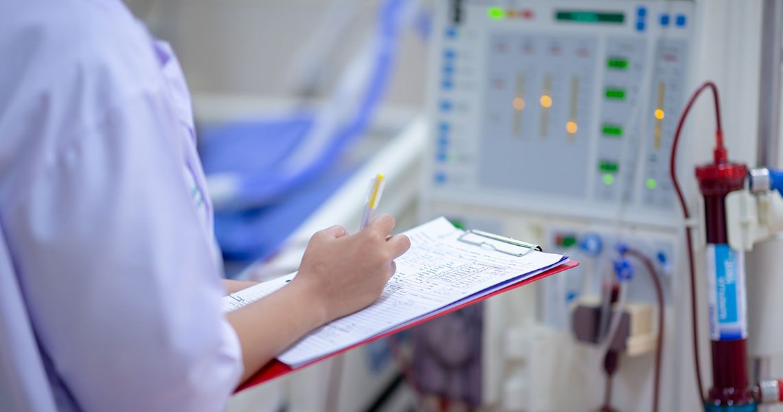 A physician takes notes in front of a dialysis machine