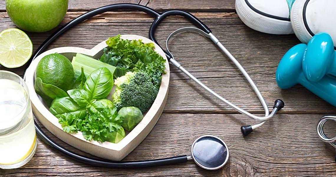 heart shaped bowl with healthy veggies and a stethescope laying around it