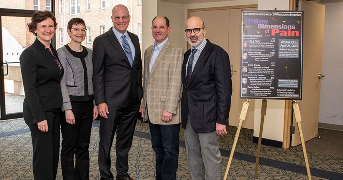 Five Neuroscience symposium speakers standing together next to a posterboard