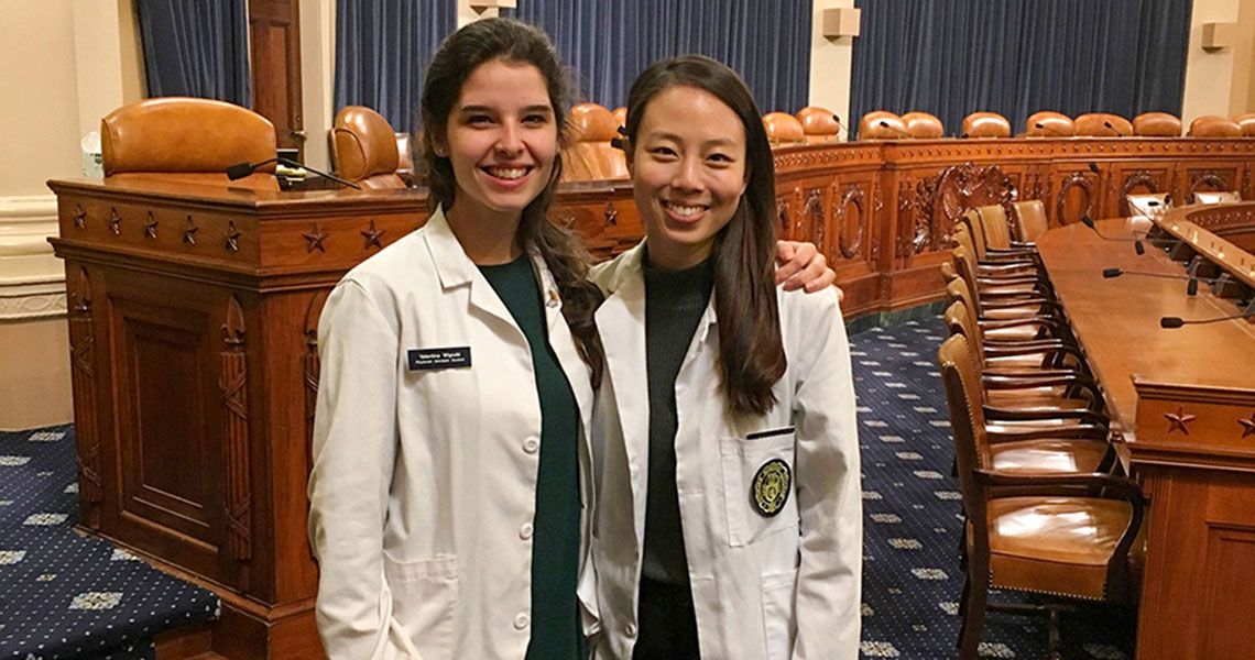 Kristen Schoenike and Garnetta Gonzalez wearing white coats and standing together in a government building