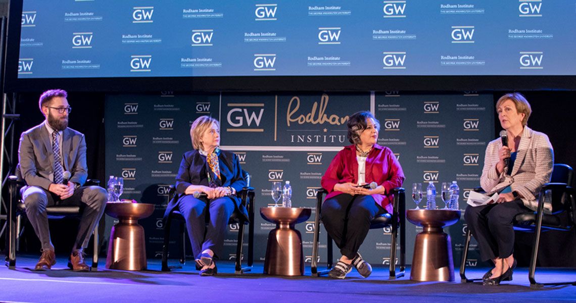 Four panelists sit together in front of a 'GW Rodham Institute' labeled wall