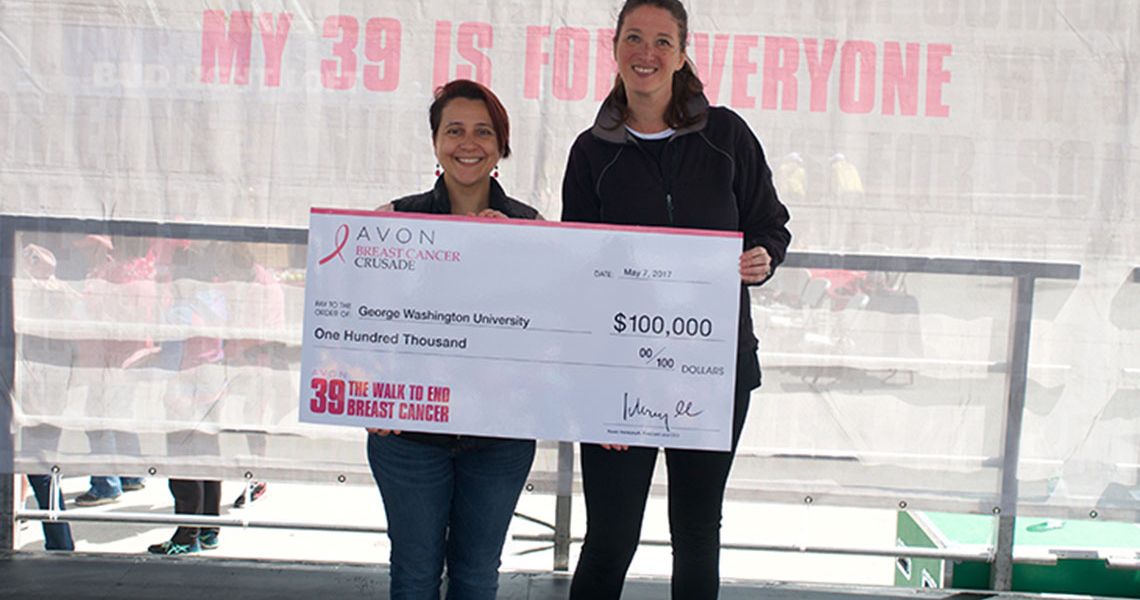 Mandi Pratt-Chapman and a woman standing with a large check from the Avon Foundation