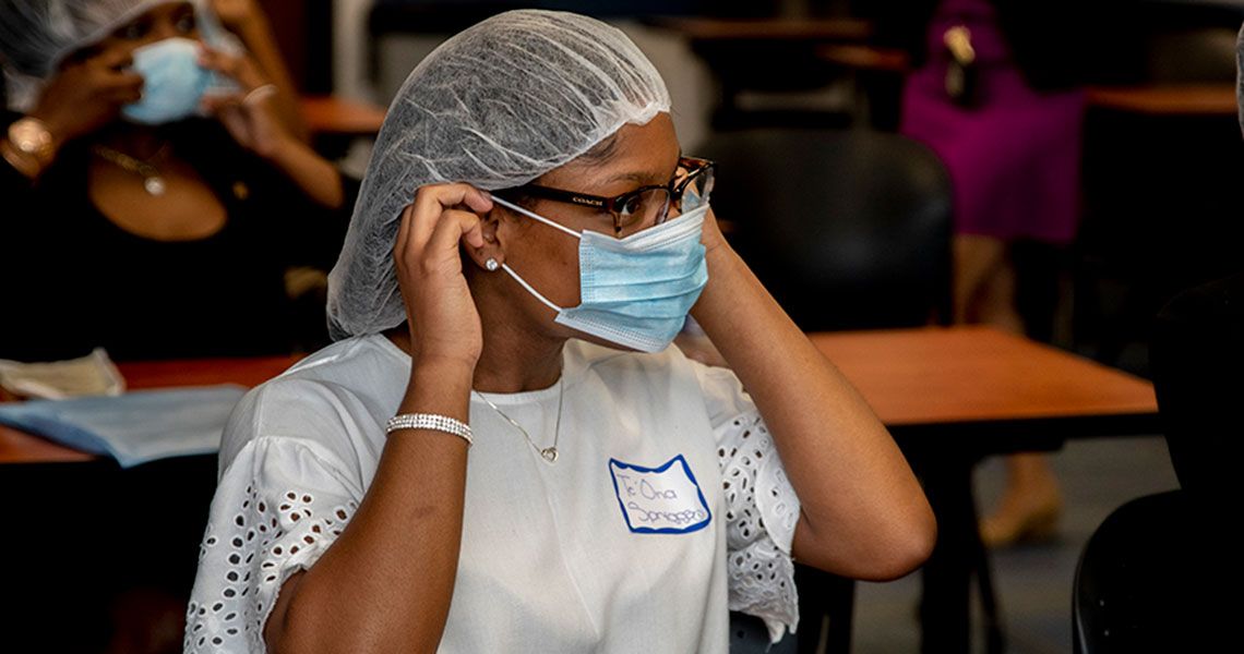 A DC HEAL participant putting on a facemask and hairnet