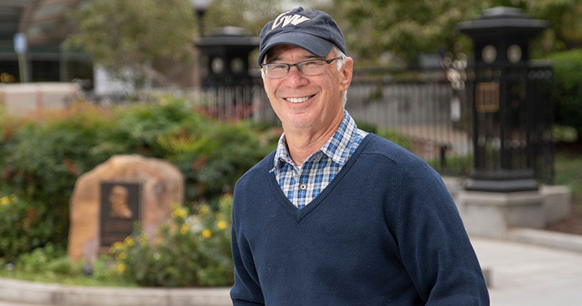 Dr. Gordon Moshman wearing a GW hat and posing for a portrait outdoors