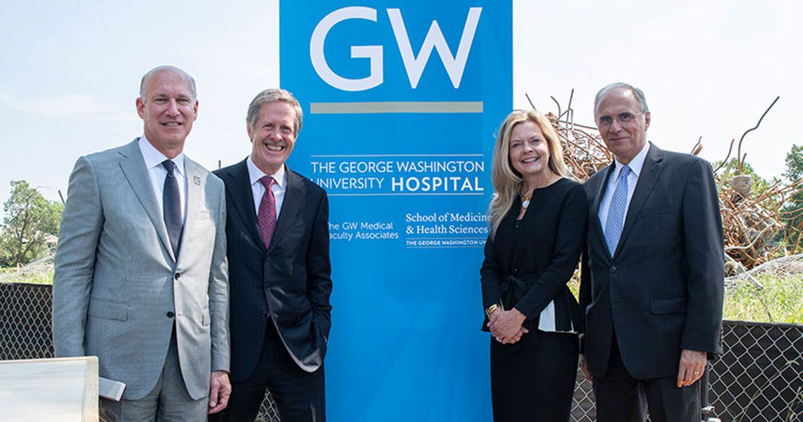 Four SMHS faculty stand beside the construction site of a new GW Hospital complex