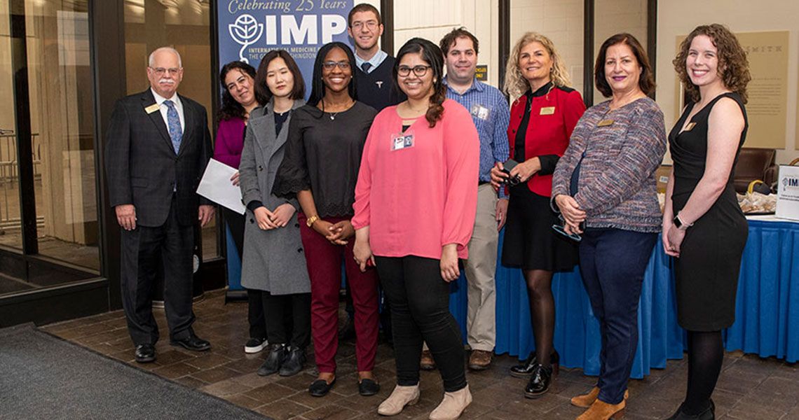 A group of people involved with the International Medicine Programs standing in front of a table and smiling