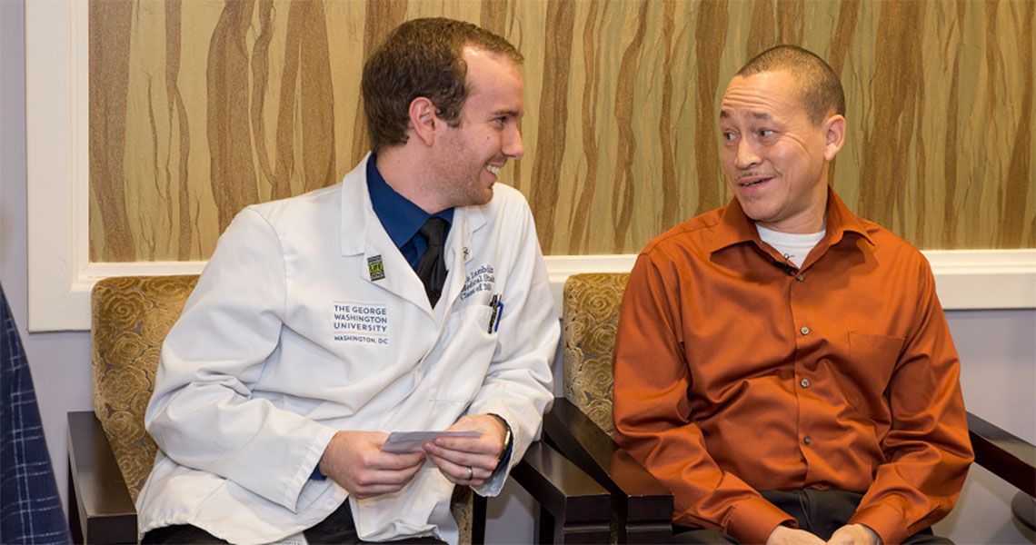 Keith Lambdin sitting with and smiling at a patient