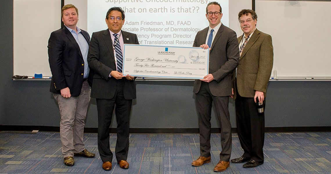 Drs. Adam Friedman and Eduardo Sotomayor holding a large check