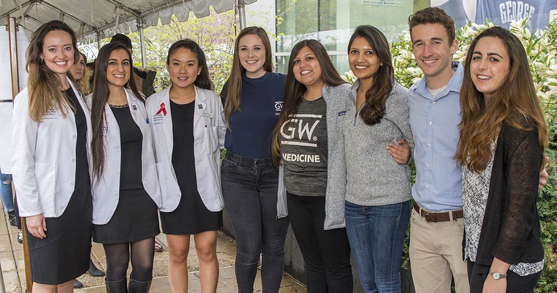 Several GW medical students standing together beneath an event tent