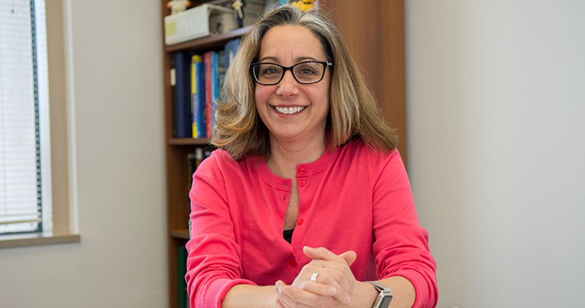 Dr. Marcia Firmani sitting with her hands together and smiling