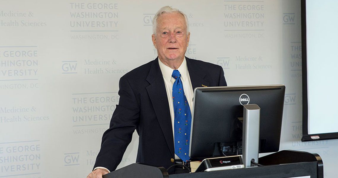 Dr. Harry C. Miller standing at a podium with a computer monitor