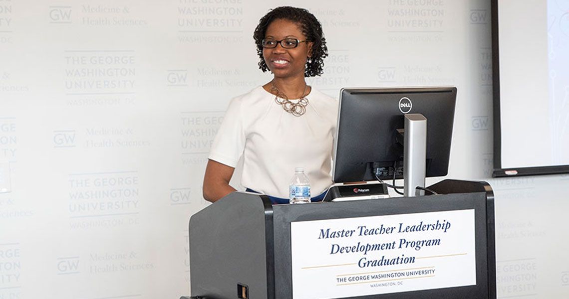 A woman standing at a podium during the GW Master Teacher Leadership Development Program