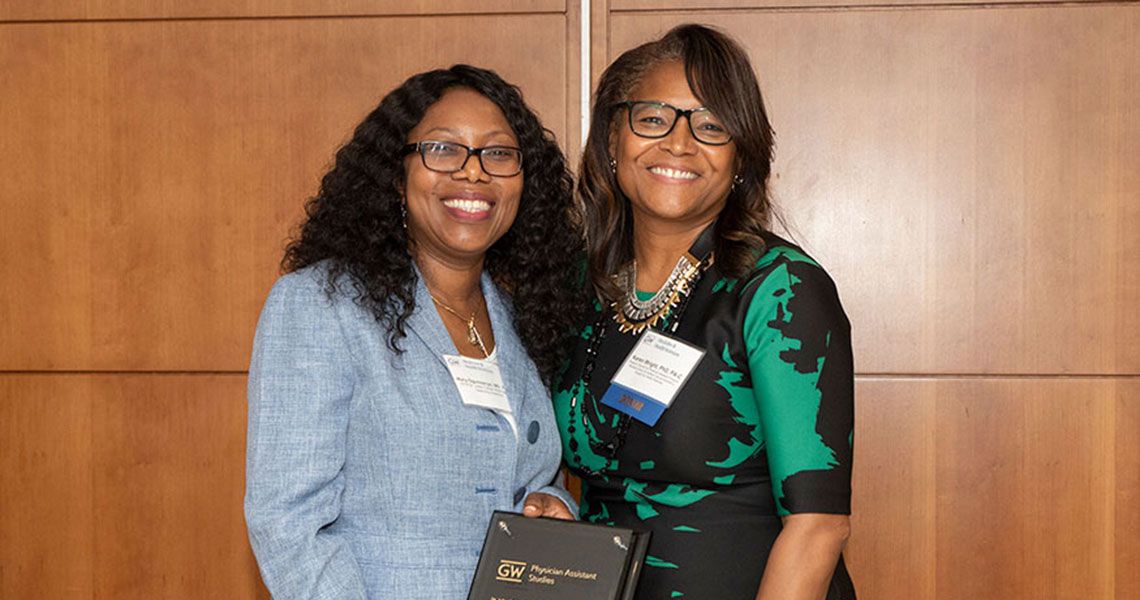 Drs. Mary A. Ogunsanya and Karen Wright standing with each other and holding an award