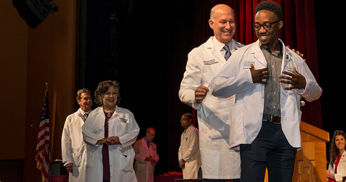 MD student receives his short white coat from SMHS Dean Jeffrey Akman