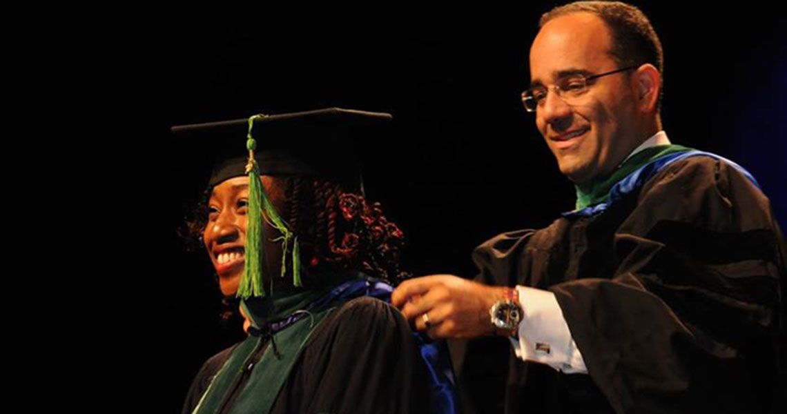 Beatrix Ohienmhen in graduation regalia being hooded by Dr. Babak Sarani