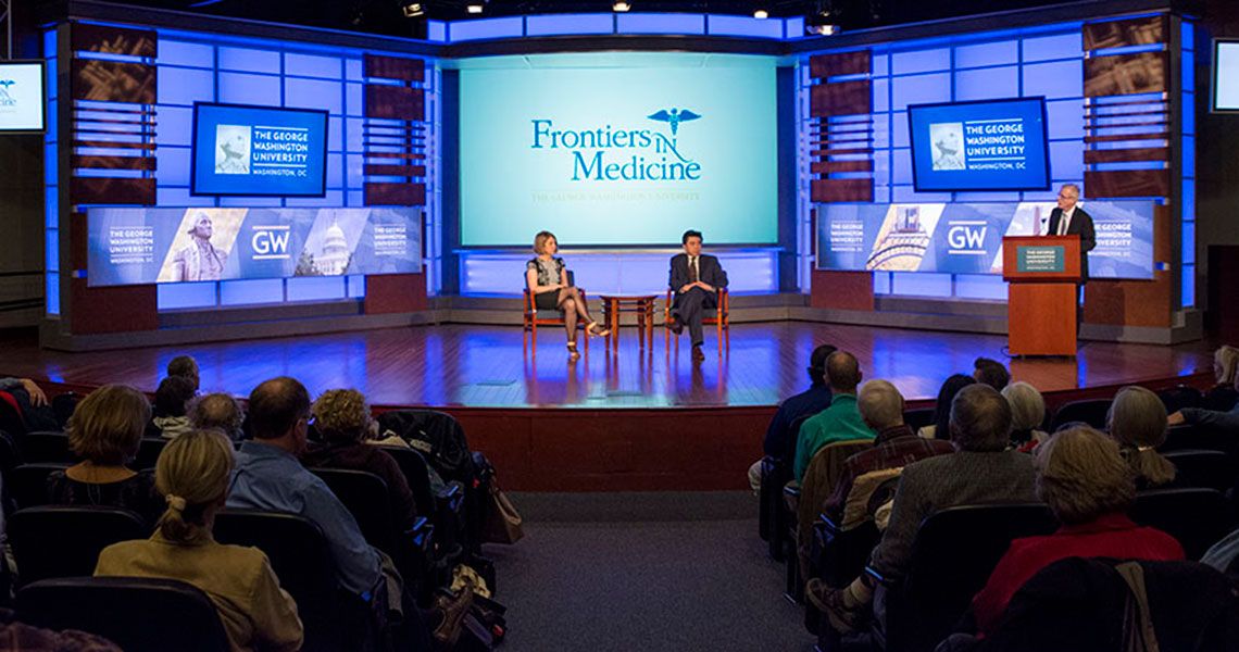 Two GW faculty sitting on stage before an audience