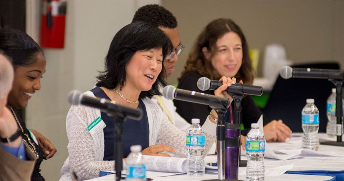 Participants in the M.D. Program Obesity Summit sitting at a table with microphones