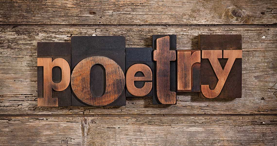 Wood letter blocks forming the word 'poetry' on a wood surface